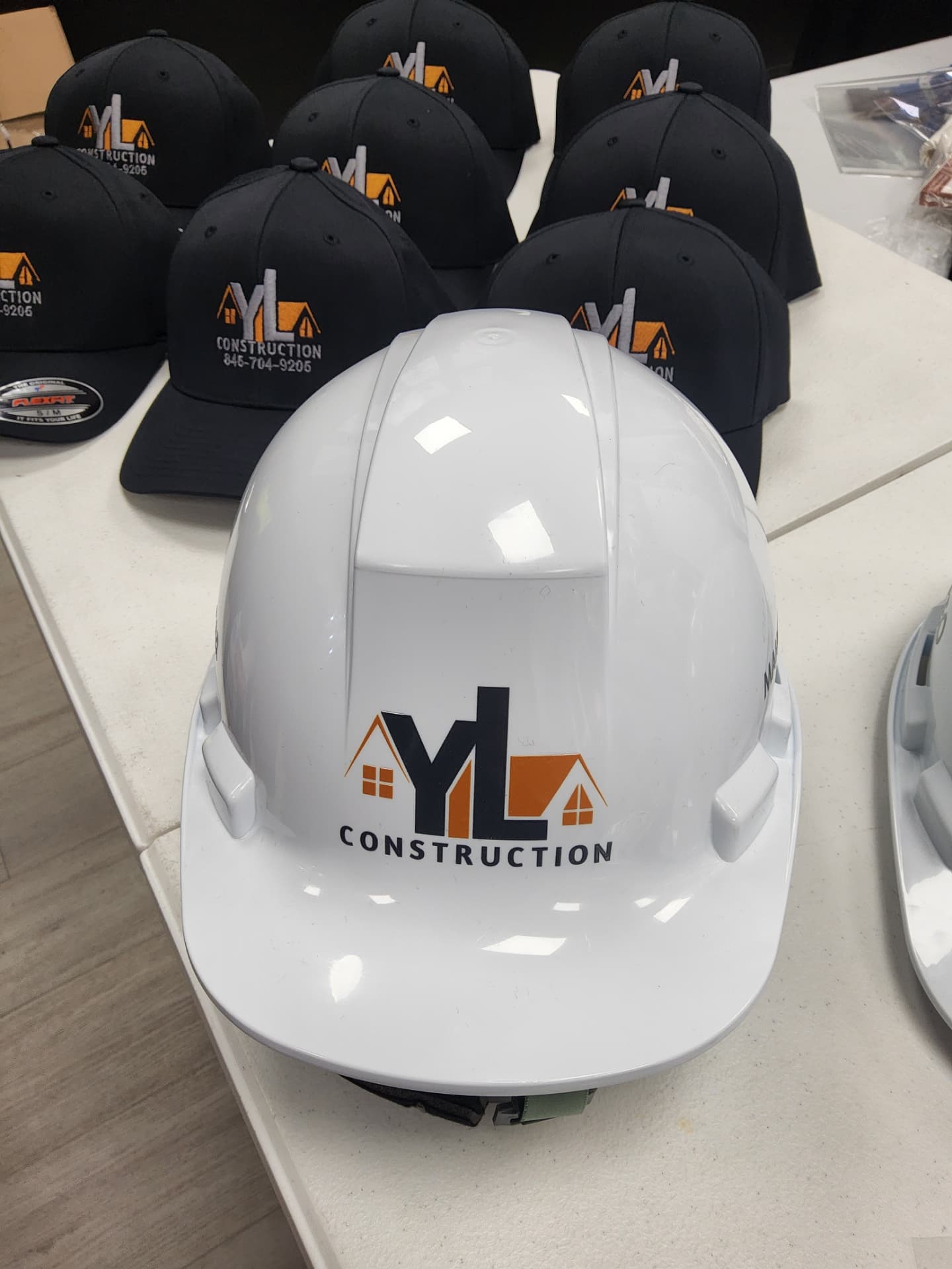 YL Construction branded hard hats and embroidered caps