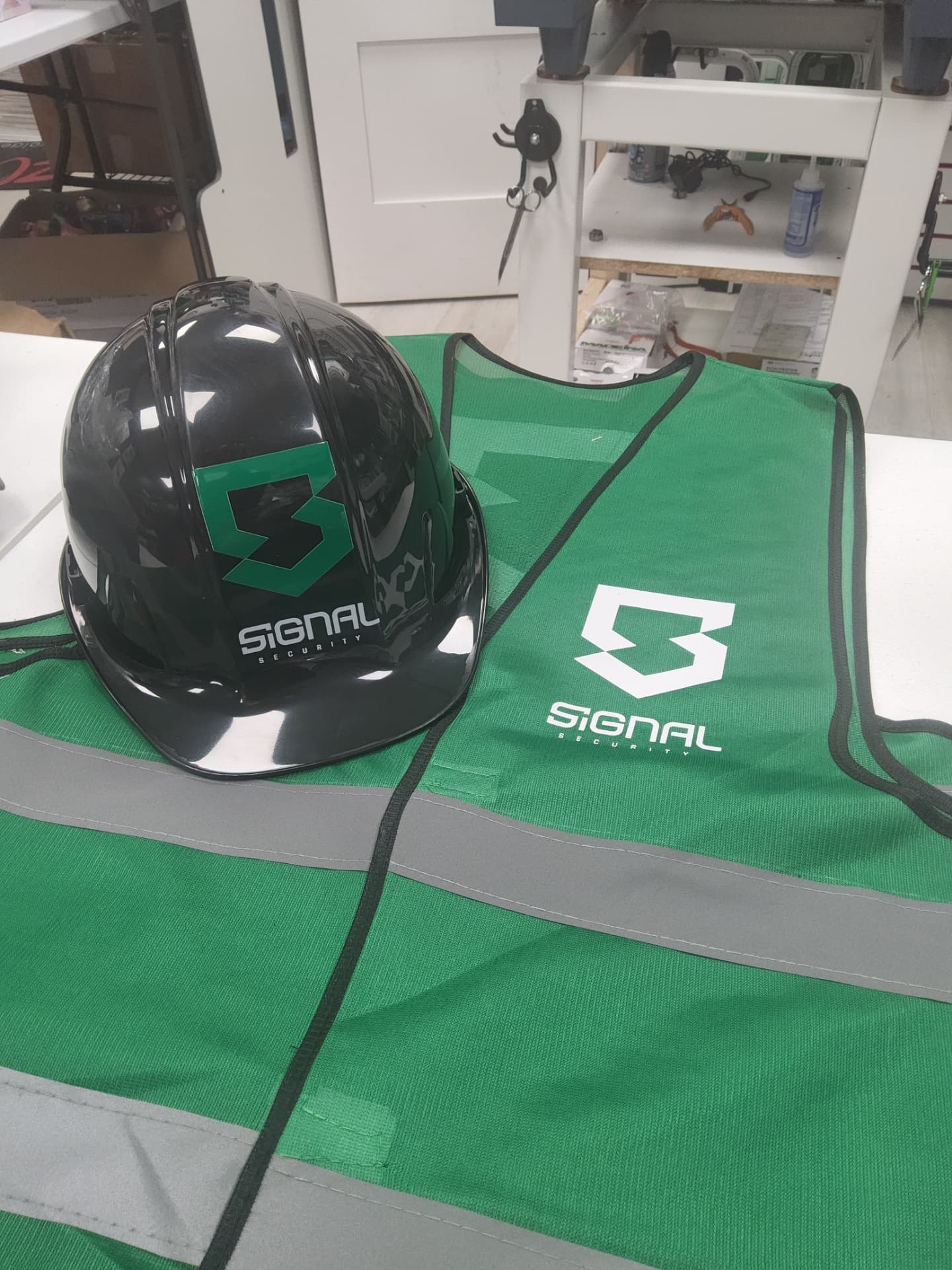 Signal Security branded black hard hat and green hi-vis safety vest