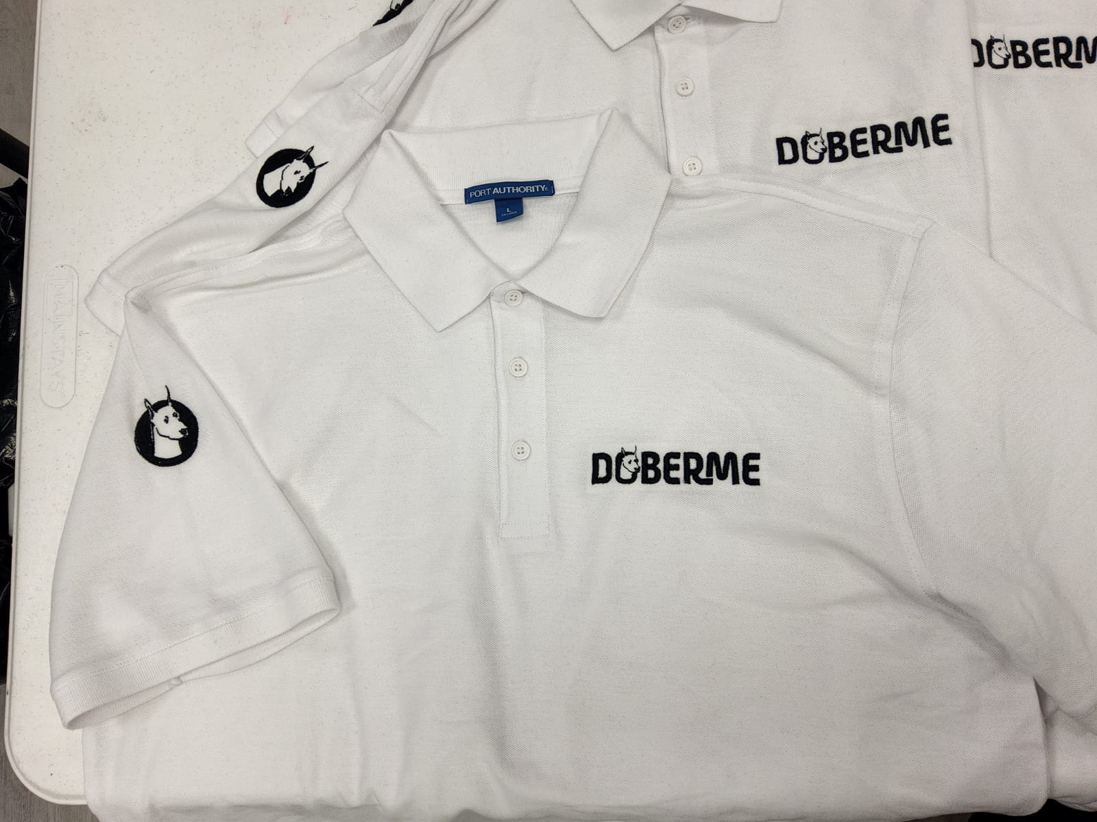 Doberme white polos with black embroidered chest and sleeve logos
