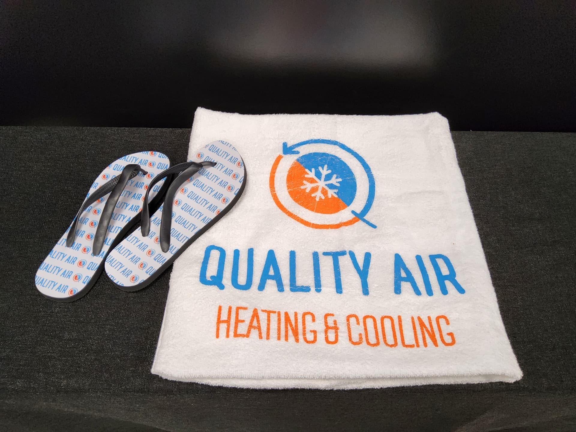 Quality Air Heating & Cooling printed white towel and branded flip flops